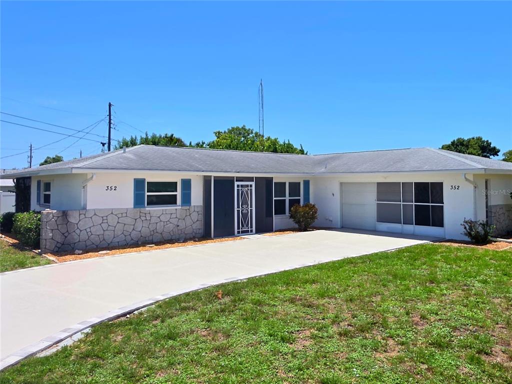 A single-story house with a white exterior, stone facade, and a concrete driveway — 352 PINE TREE ROAD, VENICE, FL