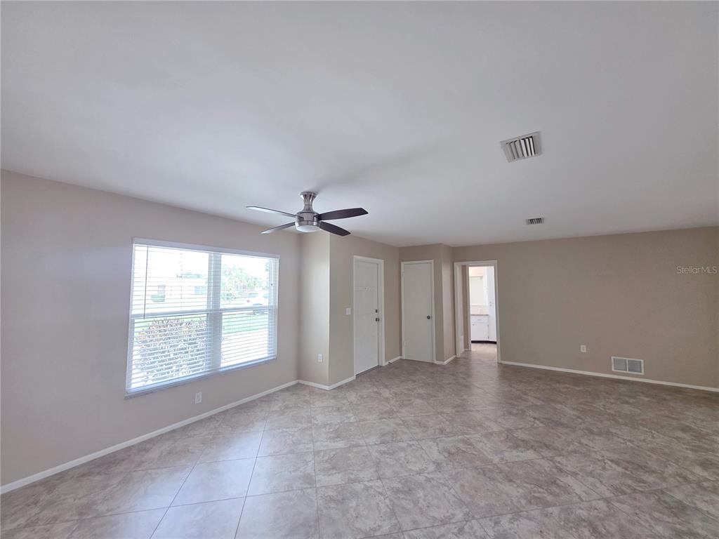 A spacious room with light-colored tile flooring, a ceiling fan, and a large window — 352 PINE TREE ROAD, VENICE, FL