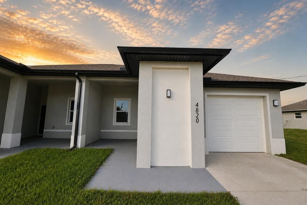 A modern single-story house exterior features a white stucco facade, a garage, and a porch — 4820 24TH STREET SW, LEHIGH ACRES, FL