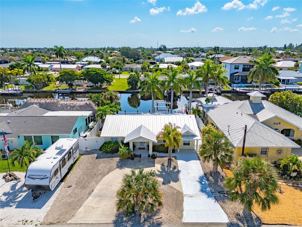 An aerial view shows a single-story house with a white metal roof and a driveway — 12262 BOAT SHELL DR, MATLACHA ISLES, FL