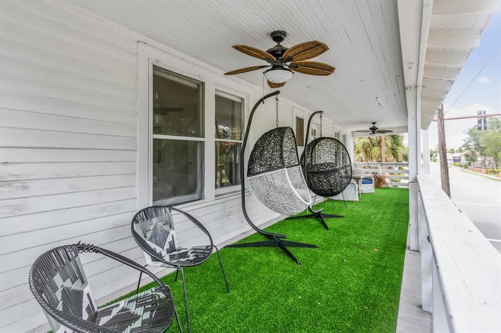 A covered porch features artificial turf flooring, two hanging egg chairs, and two accent chairs — 218 SAN MARCO AVENUE, ST AUGUSTINE, FL