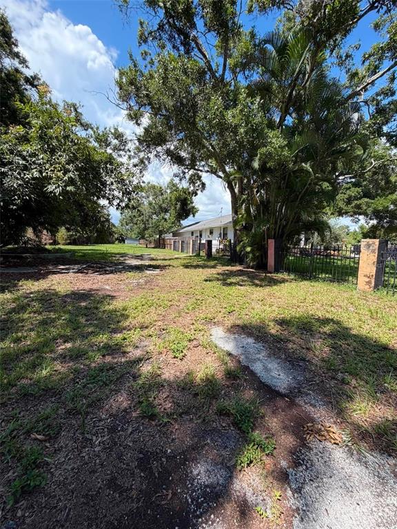 A grassy, partially shaded lot features a distant house and a black metal fence — 4365 78TH AVENUE N, PINELLAS PARK, FL