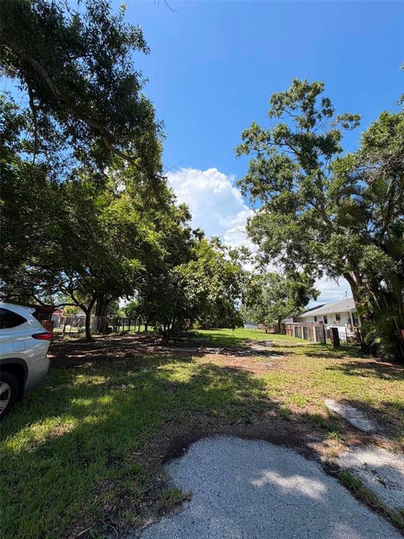 A grassy, tree-lined lot sits next to a residential house and a parked vehicle — 4365 78TH AVENUE N, PINELLAS PARK, FL