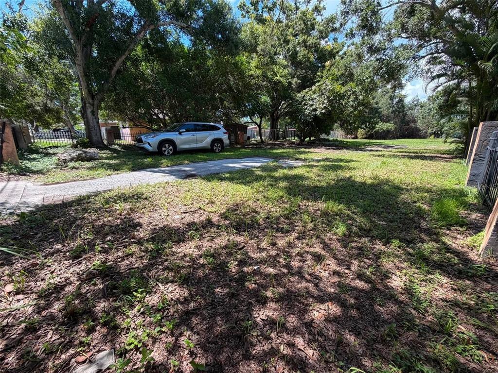 A silver SUV is parked on a gravel driveway in a grassy, tree-lined yard — 4365 78TH AVENUE N, PINELLAS PARK, FL