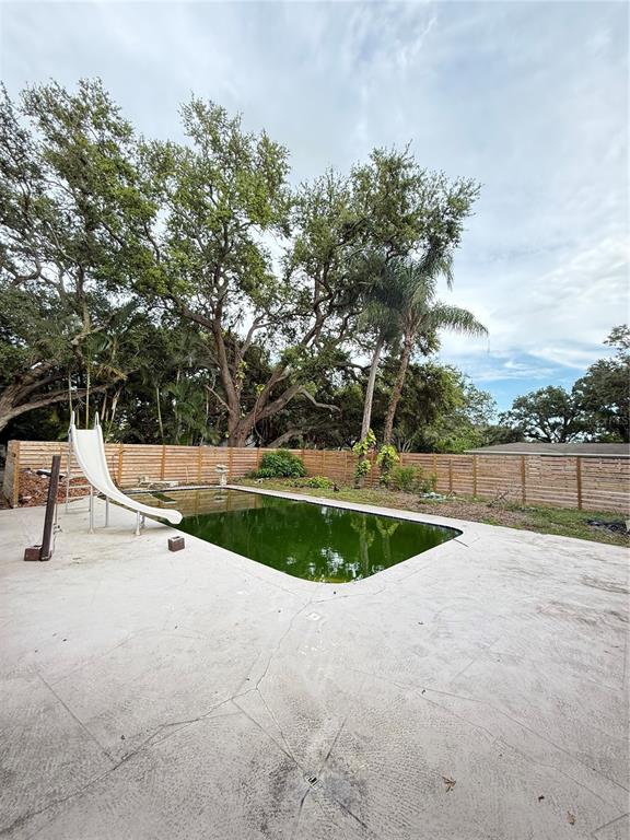 A single-story house with a garage sits behind large oak trees on a grassy lot — 384 LENTZ ROAD, BELLEAIR BLUFFS, FL