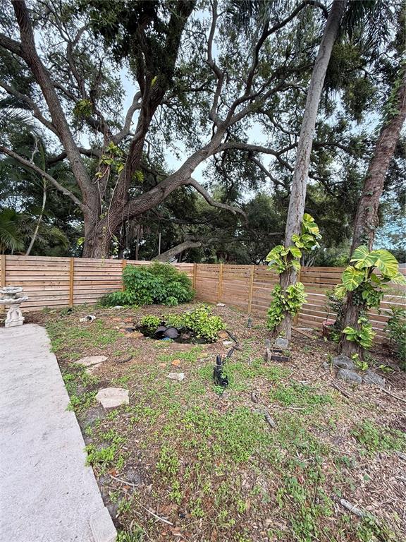 A backyard features a green swimming pool with a slide and a stone fountain — 384 LENTZ ROAD, BELLEAIR BLUFFS, FL