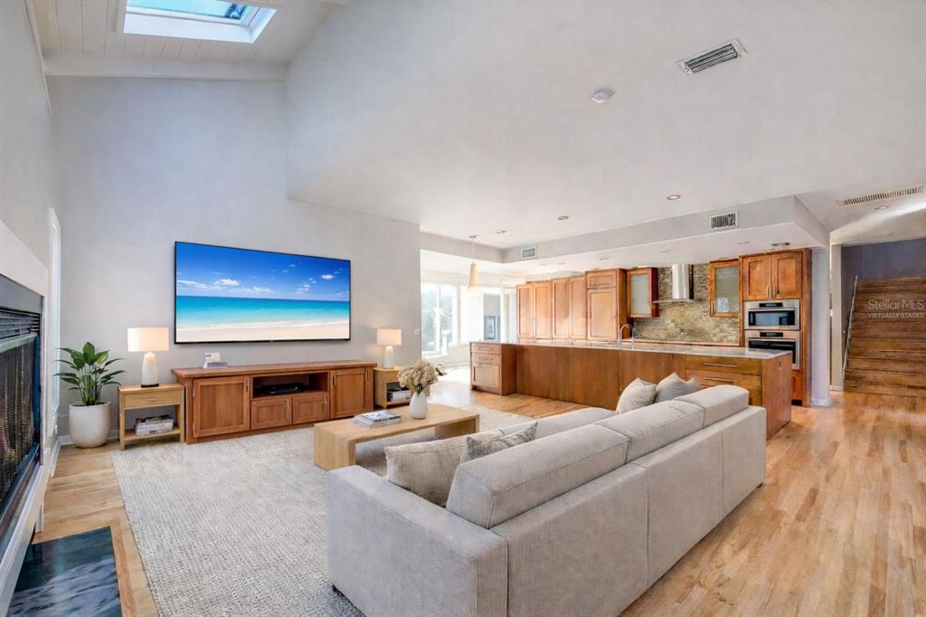 A living room with a vaulted ceiling, skylight, fireplace, and an open kitchen with wood cabinetry — 1351 WILLOW BROOK DR, PALM HARBOR, FL