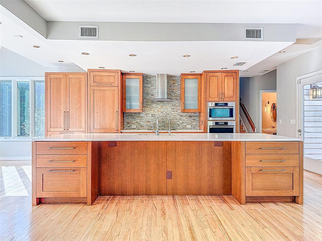 A living room with a vaulted ceiling, skylight, fireplace, and an open kitchen with wood cabinetry — 1351 WILLOW BROOK DR, PALM HARBOR, FL