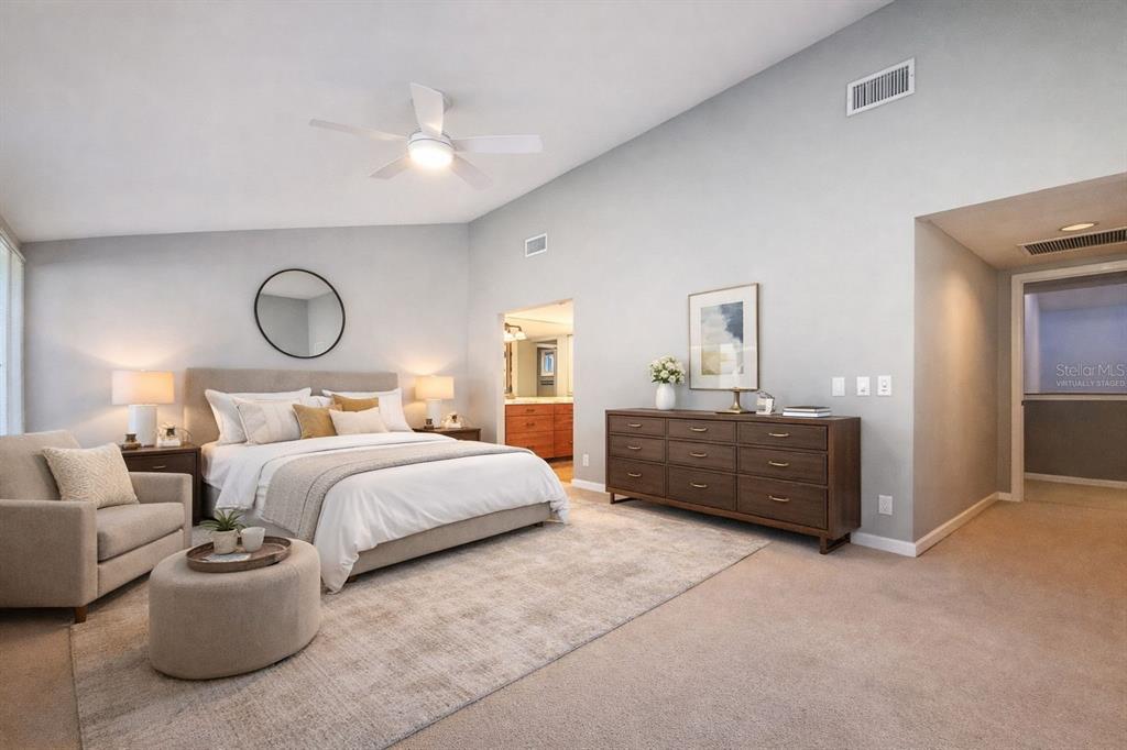 A bedroom features a bed, armchair, dresser, and vaulted ceiling with a ceiling fan — 1351 WILLOW BROOK DR, PALM HARBOR, FL