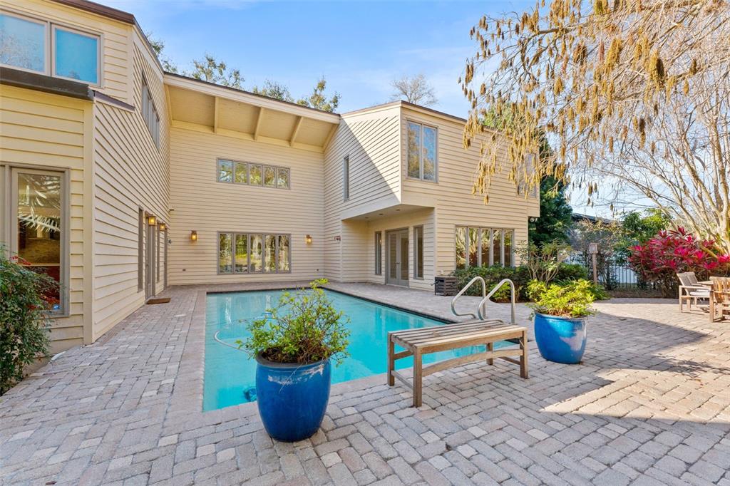 A two-story house with light siding overlooks a rectangular swimming pool on a brick patio — 1351 WILLOW BROOK DR, PALM HARBOR, FL