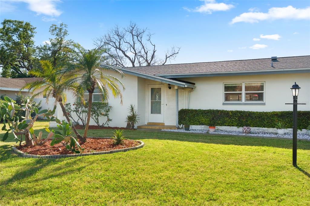 A single-story house with a white exterior, a palm tree, and a front lawn — 1768 HARBOR CIRCLE E, LARGO, FL