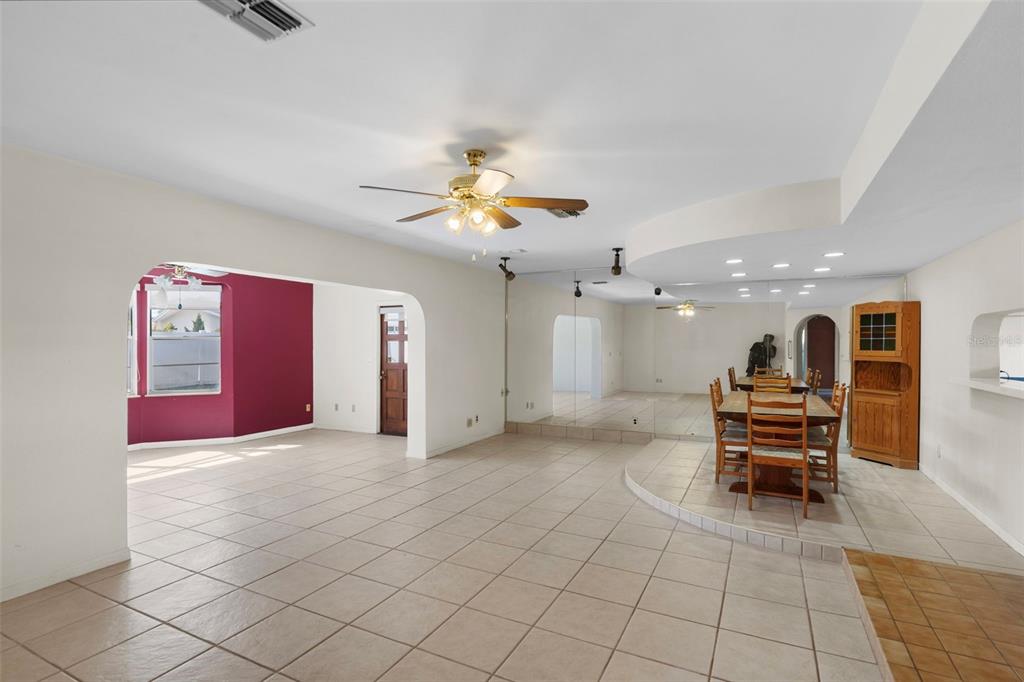 A spacious room with tiled floors, a dining area on a raised platform, and mirrored walls — 1768 HARBOR CIRCLE E, LARGO, FL