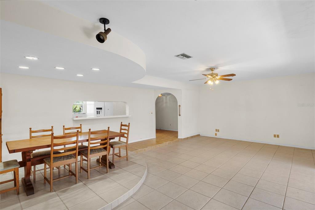 A dining area with a wooden table and chairs sits beside a large tiled room — 1768 HARBOR CIRCLE E, LARGO, FL