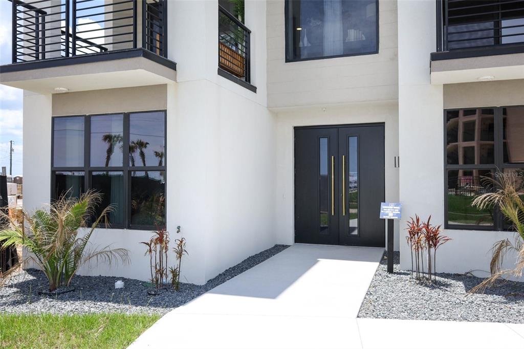 The exterior of a modern two-story house features a white facade and double front doors — 2360 OCEAN SHORE BOULEVARD UNIT 404, ORMOND BEACH, FL