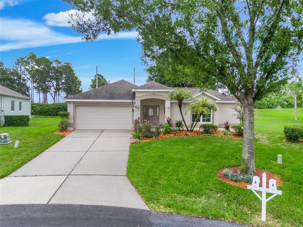 A single-story house with a beige exterior, a two-car garage, and a front lawn — 2525 NEW CASTLE COURT, CLERMONT, FL