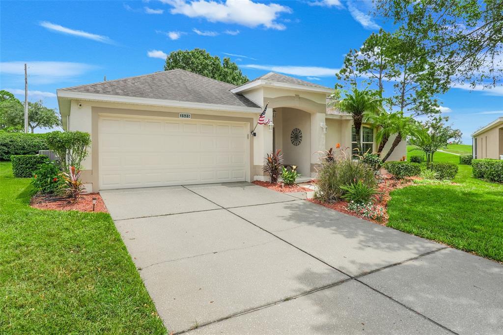 A single-story house with a beige stucco exterior, a two-car garage, and a concrete driveway — 2525 NEW CASTLE COURT, CLERMONT, FL