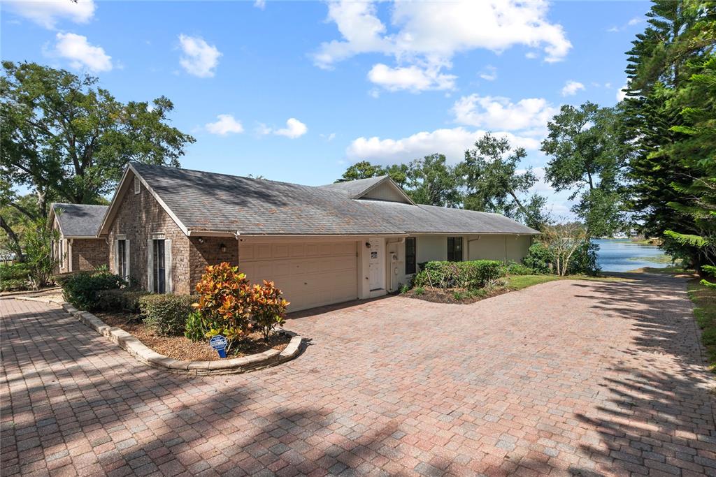 A brick house with a two-car garage and a paved driveway sits near a lake — 1111 AUDUBON WAY, MAITLAND, FL