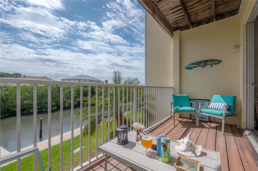 A balcony with two chairs, a small table, and a view of a canal — 119 BRENT CIRCLE, OLDSMAR, FL