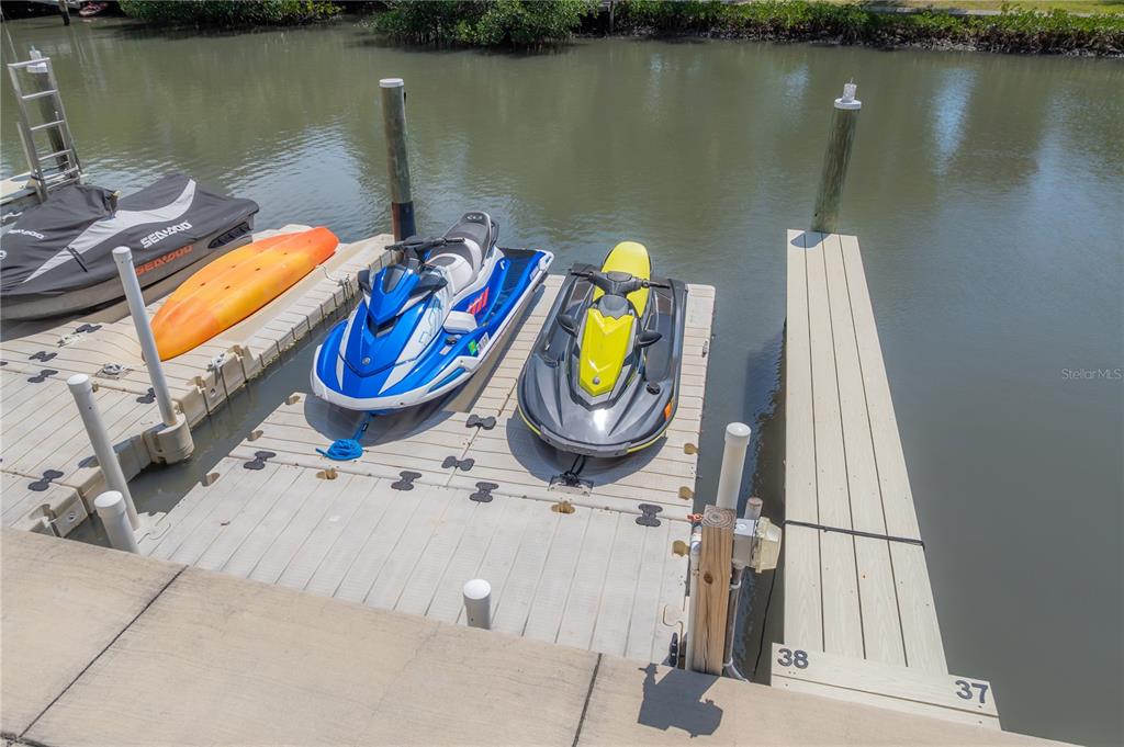 A floating dock holds two jet skis and an orange kayak on a canal — 119 BRENT CIRCLE, OLDSMAR, FL