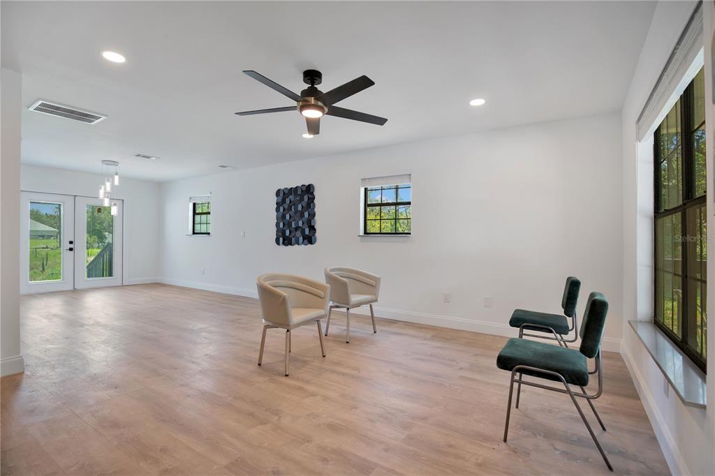 A bright, open-concept room features light wood flooring, a ceiling fan, and four chairs — 42111 CHINABERRY COURT, EUSTIS, FL