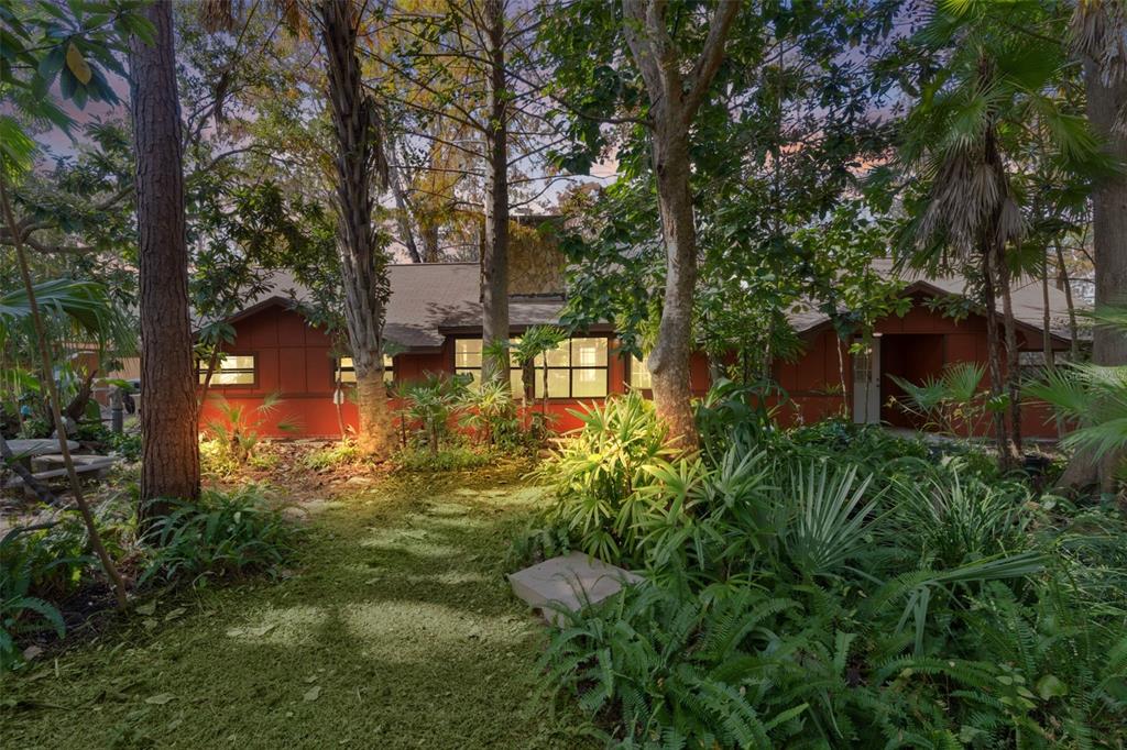 A single-story house with reddish-brown siding is nestled among trees and lush tropical landscaping — 6250 & 5942 E C 478, CENTER HILL, FL
