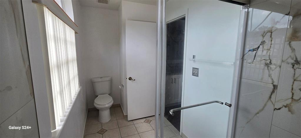 A bathroom features a toilet, a glass-enclosed shower, and tiled walls and floors — 131 CLOWSON COURT, OCOEE, FL
