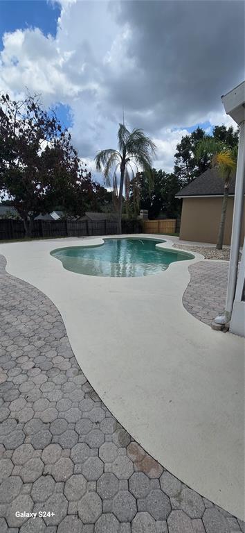 A backyard features a kidney-shaped swimming pool surrounded by a concrete deck and paver patio — 131 CLOWSON COURT, OCOEE, FL