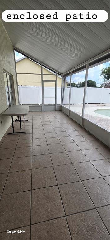 An enclosed patio features light brown tile flooring, a sloped ceiling, and screen walls overlooking a pool — 131 CLOWSON COURT, OCOEE, FL