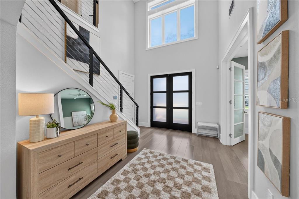 A bright entryway features a wooden dresser, a staircase with cable railings, and double doors — 1308 W PLYMOUTH STREET, TAMPA, FL