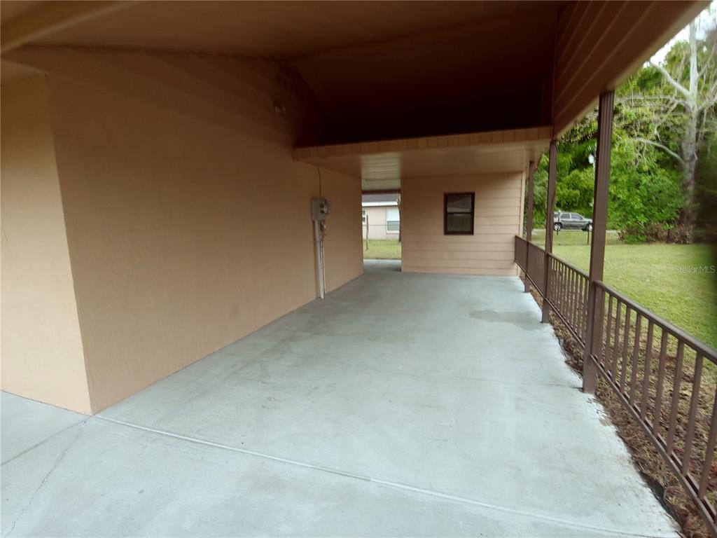 A covered concrete carport features a metal railing and a view of the yard — 3570 SE 135TH LANE, SUMMERFIELD, FL