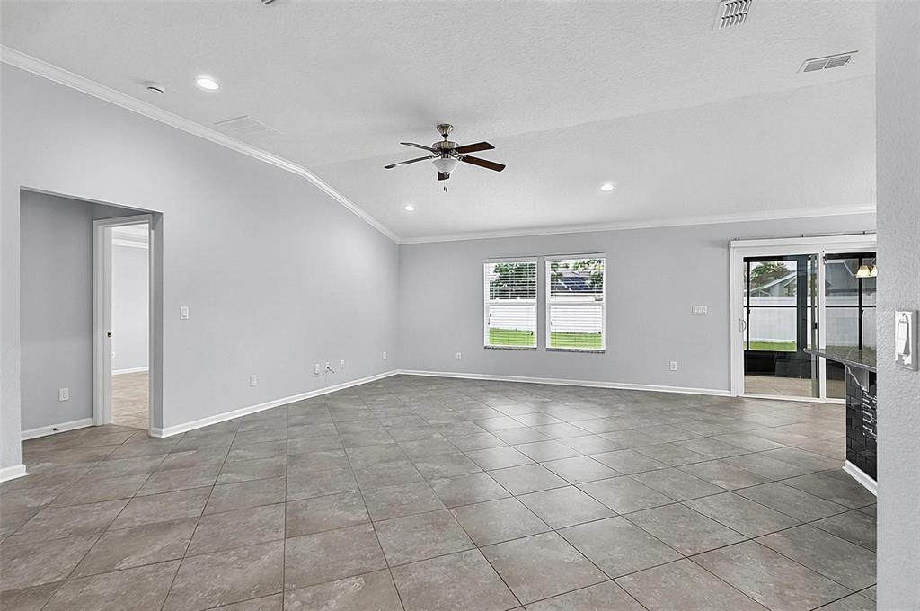 An open-concept living area features vaulted ceilings, tile flooring, and a sliding glass door — 5 GRAHAM TRAIL, PALM COAST, FL