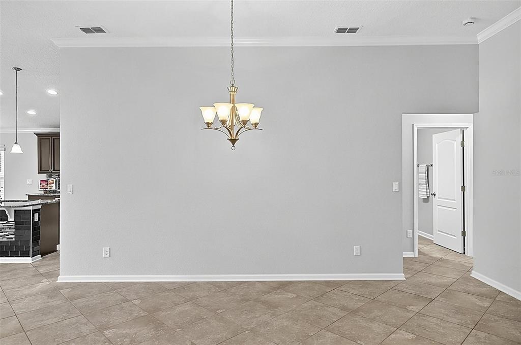 A dining area with a chandelier, light gray walls, and light brown tile flooring — 5 GRAHAM TRAIL, PALM COAST, FL