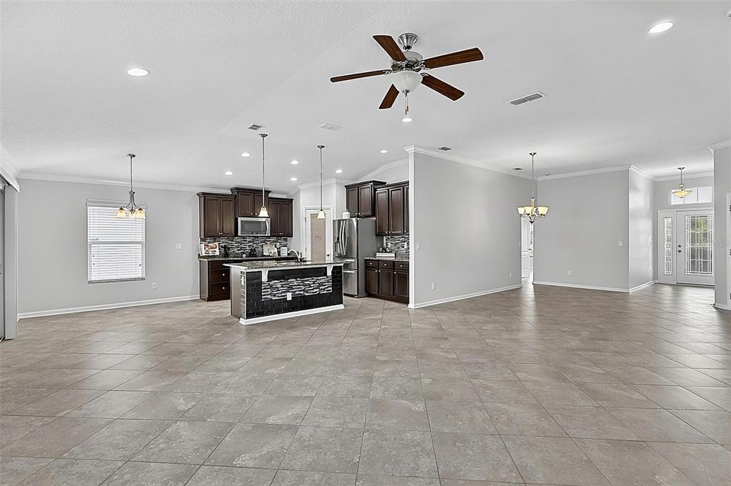 An open-concept kitchen features dark wood cabinets, a tiled island, and light-colored tile flooring — 5 GRAHAM TRAIL, PALM COAST, FL