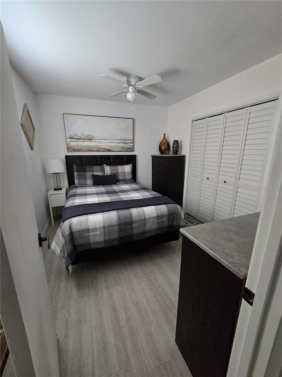 A bedroom features a plaid bed, a dark dresser, a ceiling fan, and white closet doors — 1190 PECAN STREET, KISSIMMEE, FL