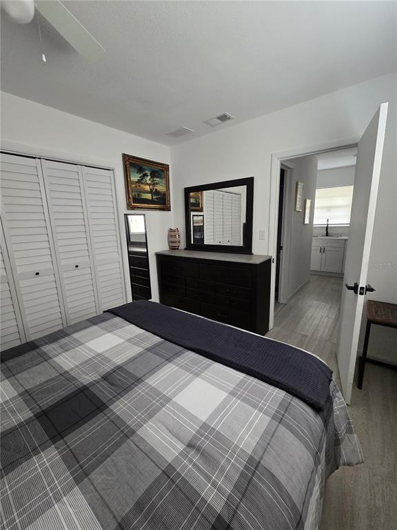 A bedroom features a plaid bedspread, a dark wood dresser with a mirror, and white doors — 1190 PECAN STREET, KISSIMMEE, FL