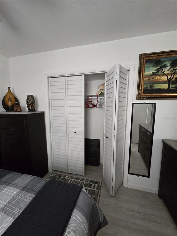 A bedroom features a white louvered closet, a dark dresser, and a framed landscape painting — 1190 PECAN STREET, KISSIMMEE, FL