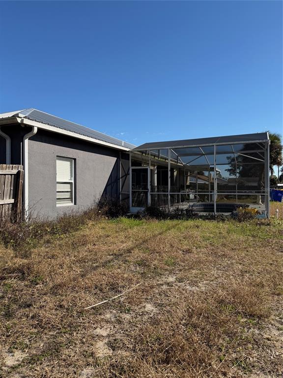 The exterior of a gray house features a screened-in pool enclosure and a fenced yard — 2904 JUNIPER DRIVE, EDGEWATER, FL