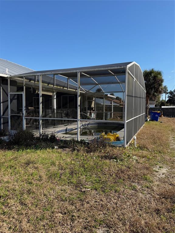 A backyard swimming pool is enclosed by a large, metal-framed screen structure — 2904 JUNIPER DRIVE, EDGEWATER, FL