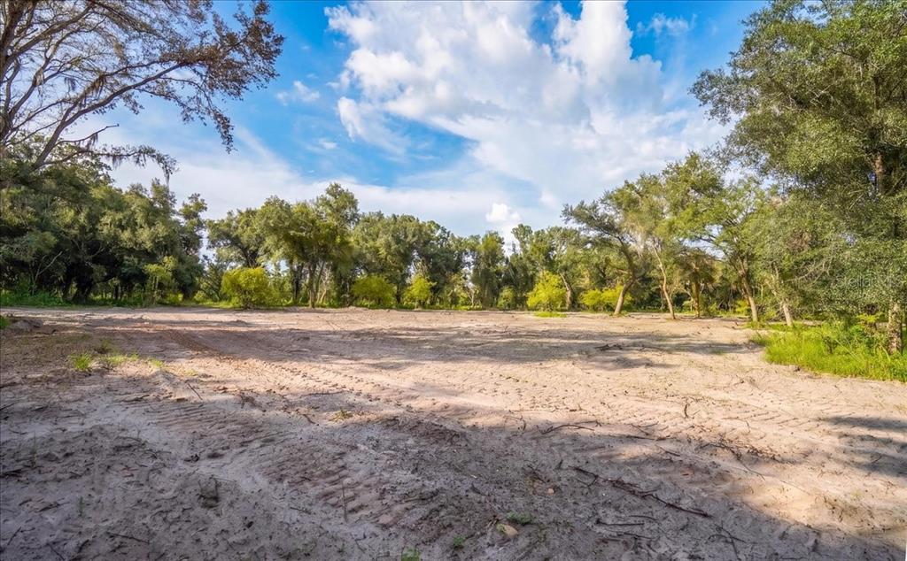 A cleared, sandy lot surrounded by mature trees under a blue sky with clouds — GILL ROAD, MYAKKA CITY, FL