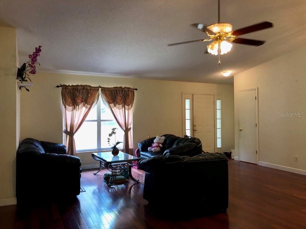 A living room features dark wood floors, two black leather sofas, and a ceiling fan — 11716 CR 672 HIGHWAY, RIVERVIEW, FL