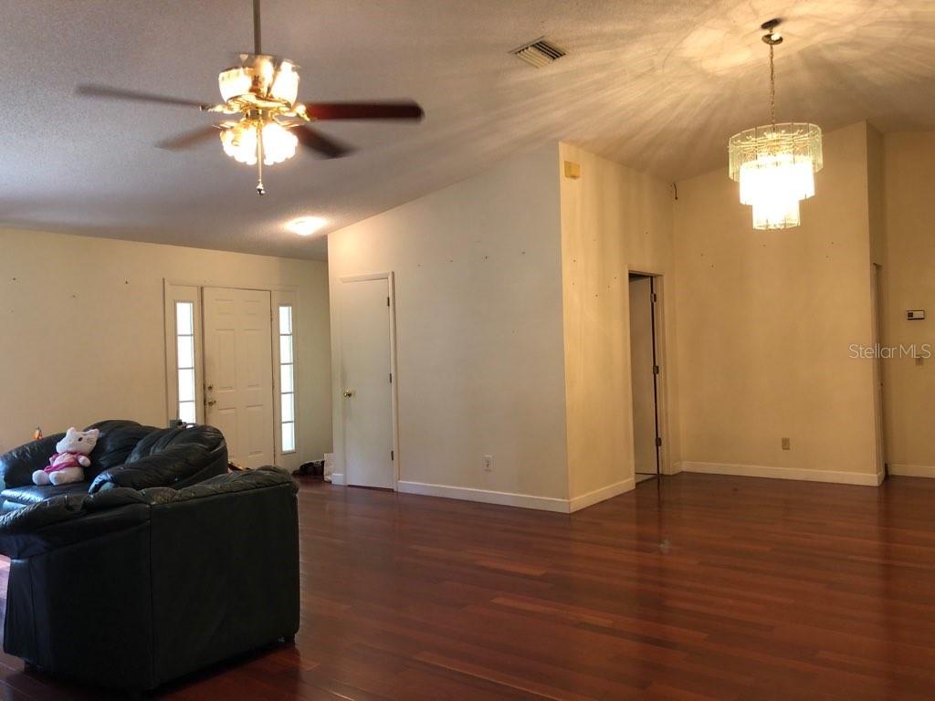 A living room with hardwood floors, a ceiling fan, and a crystal chandelier — 11716 CR 672 HIGHWAY, RIVERVIEW, FL