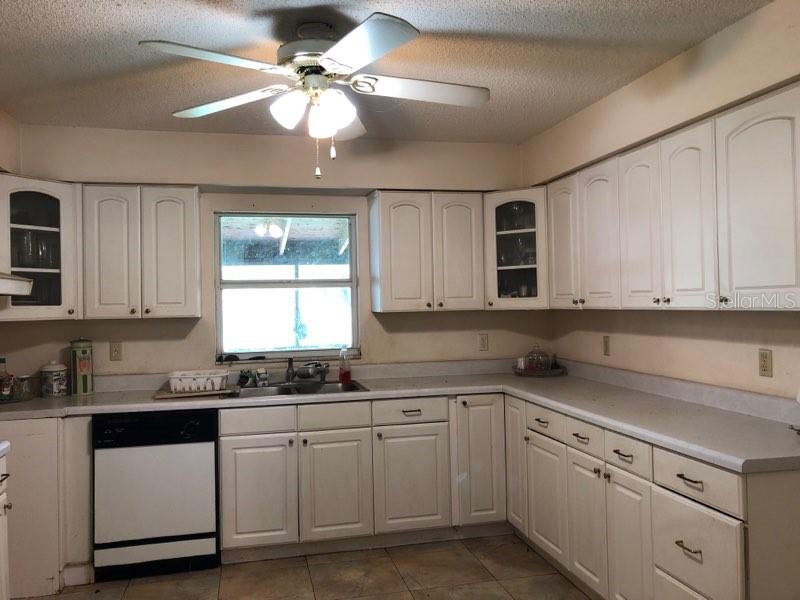 A kitchen features white cabinets, a ceiling fan, a window, and a black dishwasher — 11716 CR 672 HIGHWAY, RIVERVIEW, FL