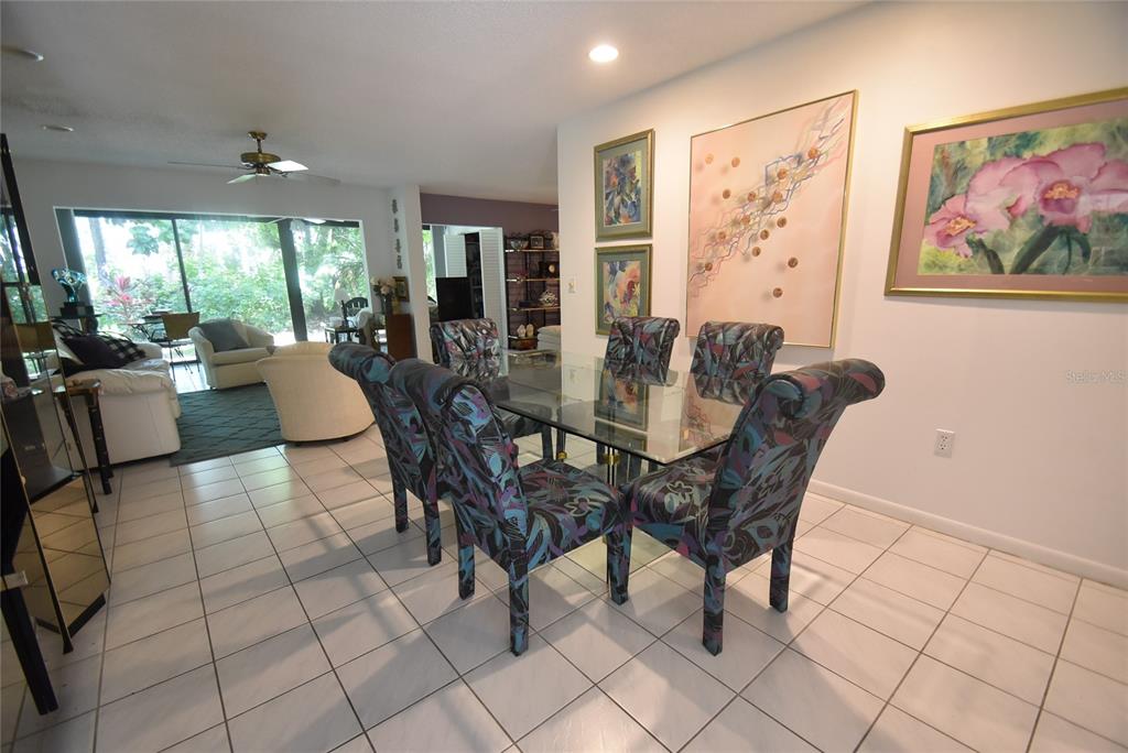 A dining room features a glass-top table with patterned chairs and tile flooring — 1709 CLOWER CREEK DRIVE UNIT BR 104, SARASOTA, FL