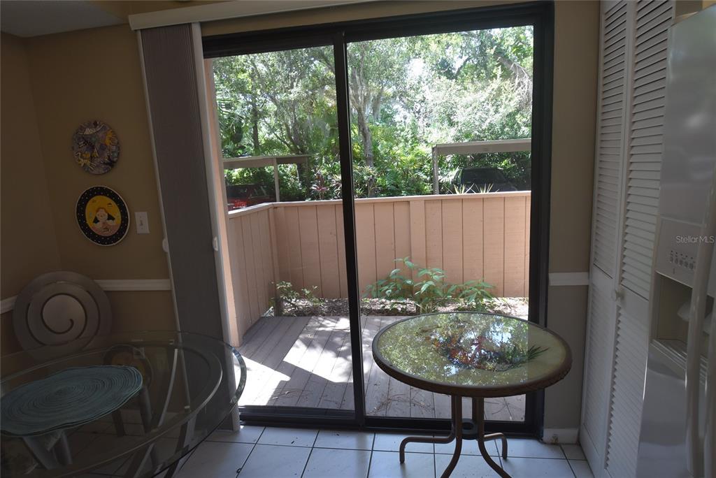 A dining area with a glass table and sliding doors opening to a private patio — 1709 CLOWER CREEK DRIVE UNIT BR 104, SARASOTA, FL