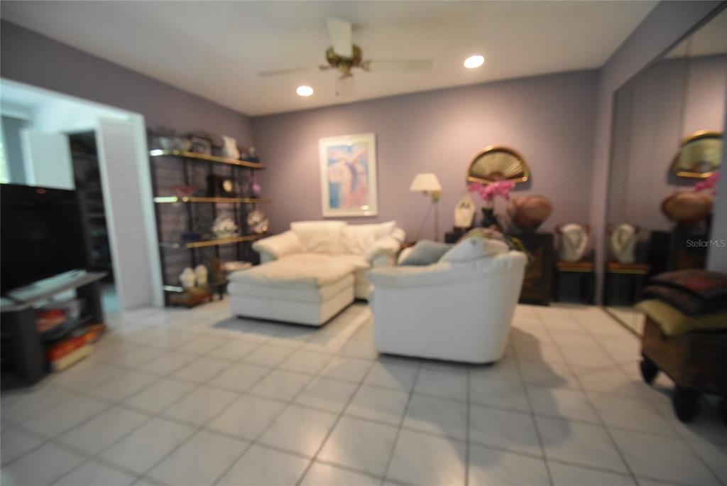 A living room features white tile floors, two white chairs, and a black metal shelving unit — 1709 CLOWER CREEK DRIVE UNIT BR 104, SARASOTA, FL