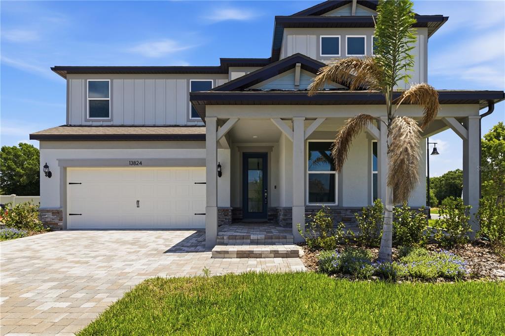 A two-story house with a paved driveway, a two-car garage, and a covered front porch — 13824 SUNLIGHT MEADOW DRIVE, RIVERVIEW, FL
