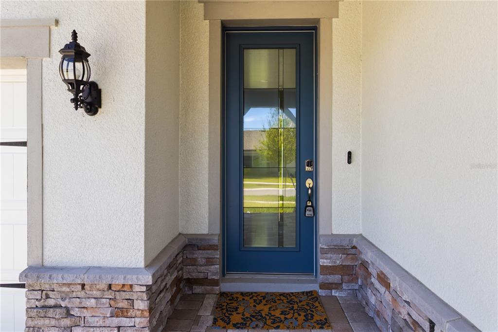 A blue front door with a glass panel is set in a stucco and stone entryway — 13824 SUNLIGHT MEADOW DRIVE, RIVERVIEW, FL