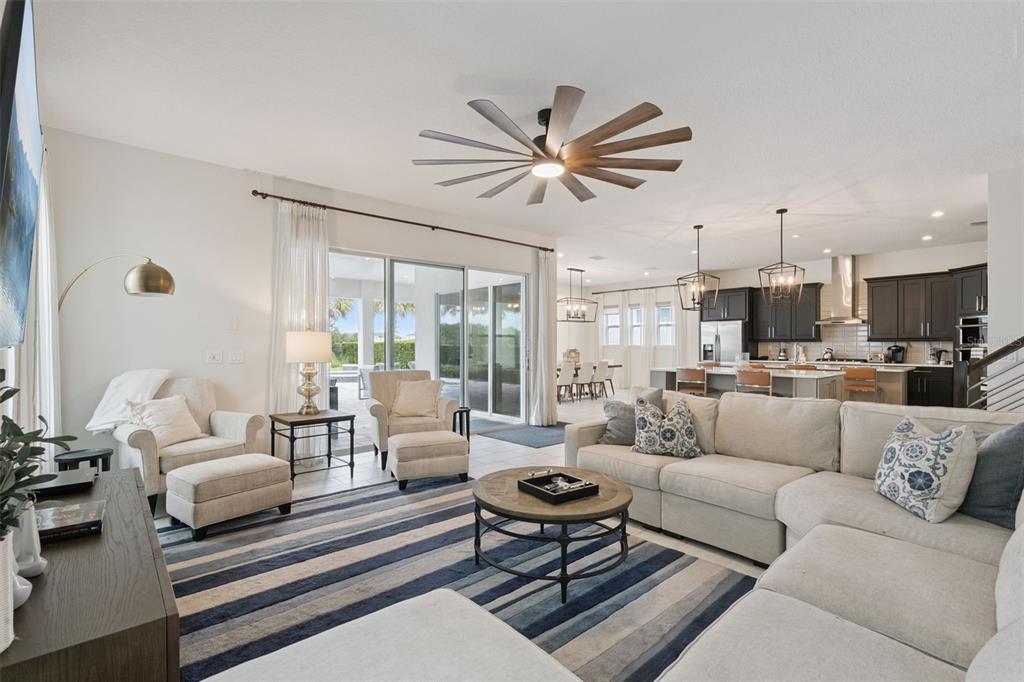 A living room with a large sectional, striped rug, and an open kitchen in back — 972 JACK NICKLAUS CT, REUNION, FL