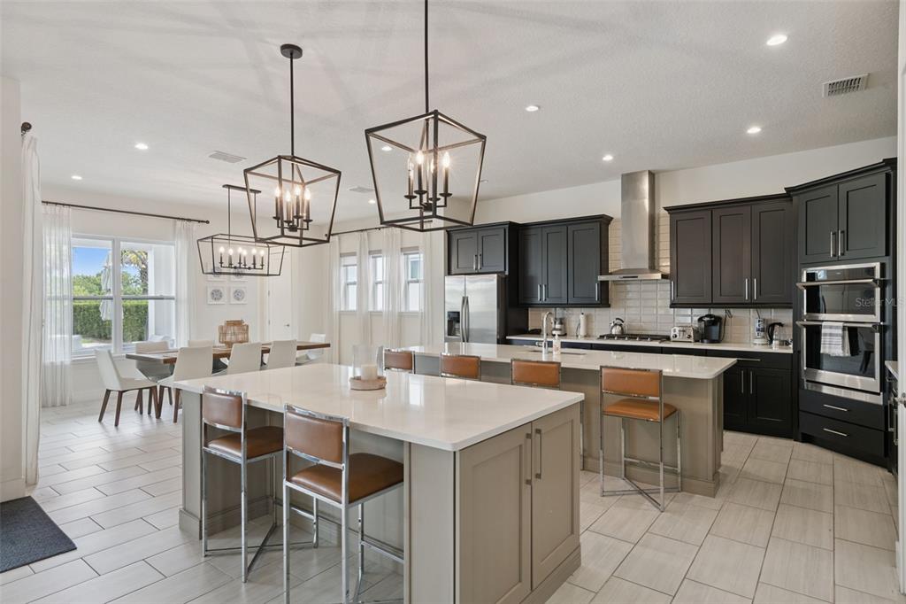 A modern kitchen features two islands, dark cabinetry, stainless steel appliances, and pendant lighting — 972 JACK NICKLAUS CT, REUNION, FL