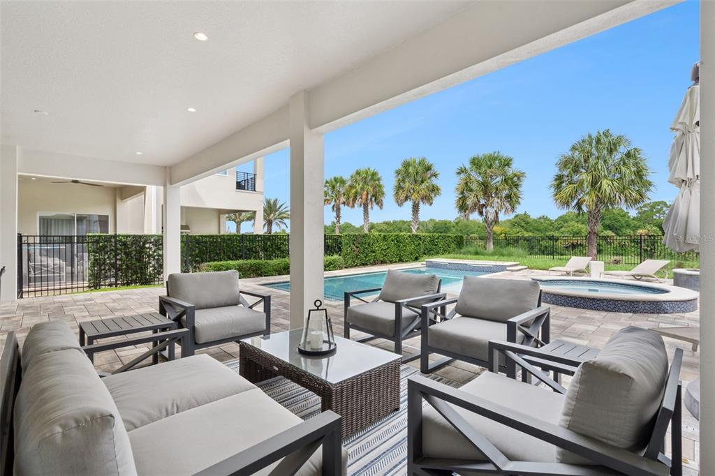 A covered patio features outdoor furniture, a swimming pool, a hot tub, and palm trees — 972 JACK NICKLAUS CT, REUNION, FL